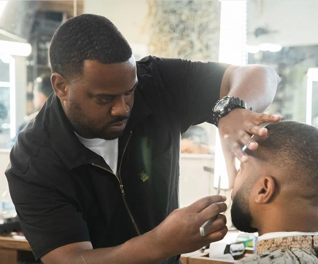 Johnnie J giving a client a precision straight razor lineup in his River North barber suite
